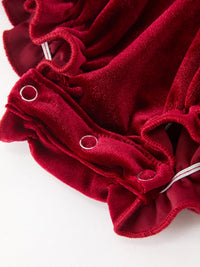 Burgundy velvet baby romper featuring ruffled details and convenient silver snap closures at the leg for easy diaper changes.
