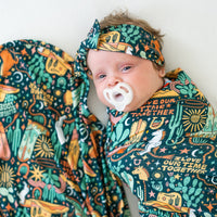 The SoftKnot Bow Wild West bamboo head-wrap on a baby with cactus and desert print.