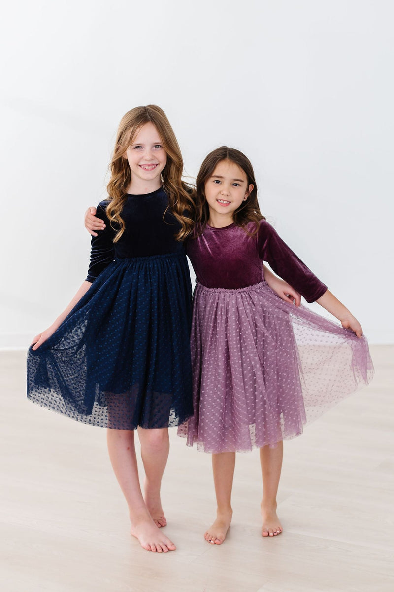 Two girls happily modeling their Amethyst Velvet Tutu Dresses with tulle skirts, showcasing the lovely design ideal for parties or holidays.