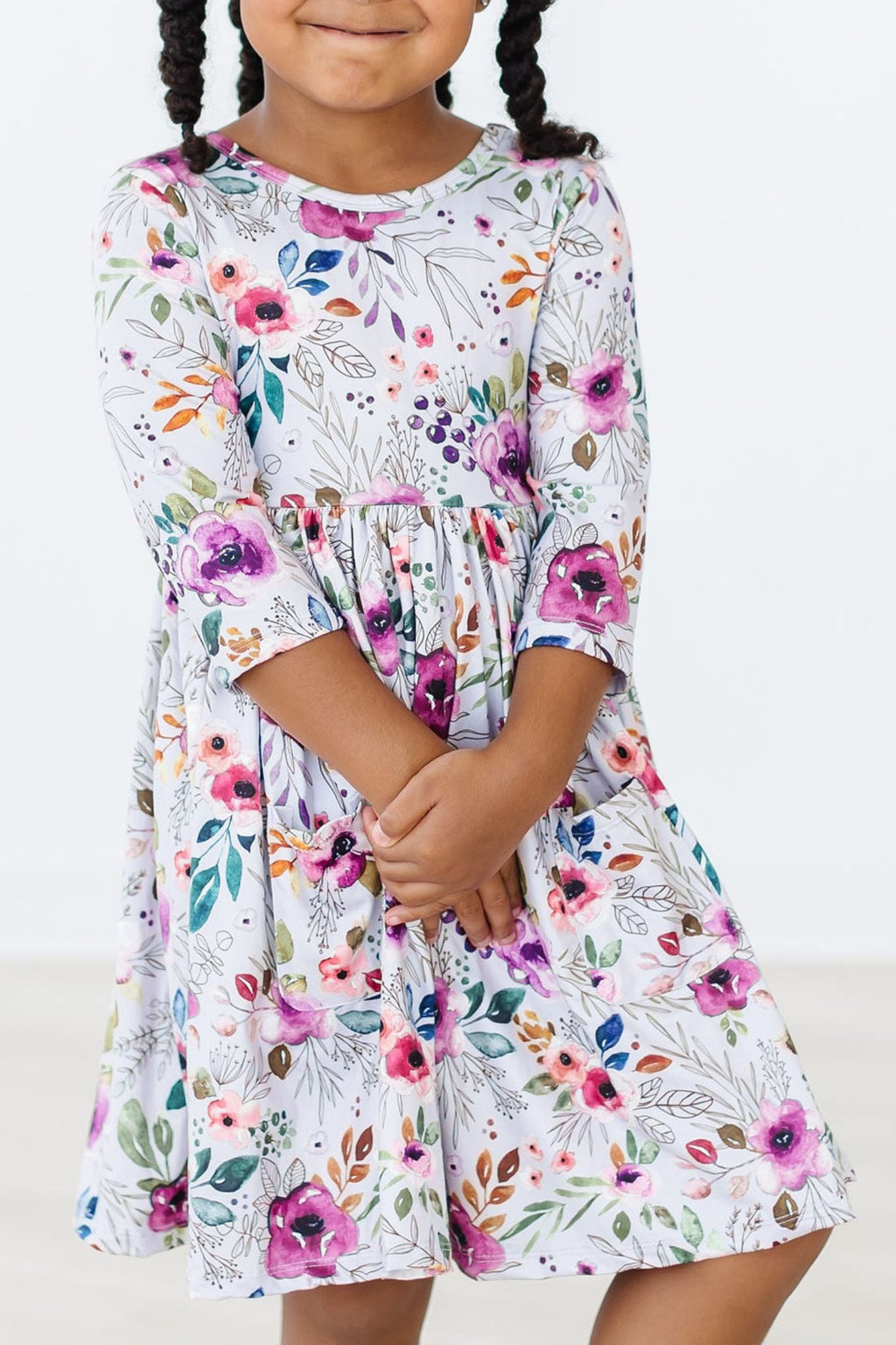 Adorable girl in the Midnight Rain 3/4 Sleeve Pocket Twirl Dress, showcasing colorful floral patterns and a cheerful smile.