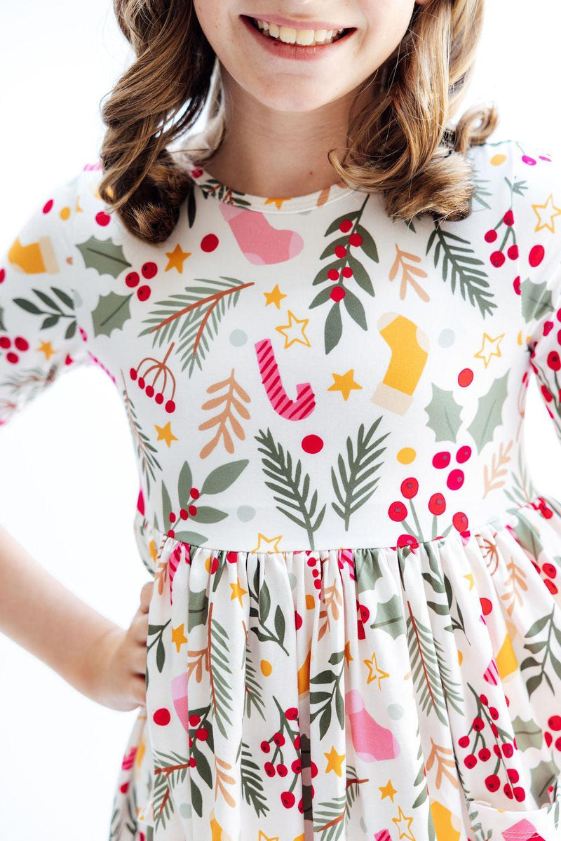 Close-up of a young girl in the 'Holly Jolly Christmas' 3/4 Sleeve Pocket Christmas Twirl Dress for Girls, showcasing the colorful holiday-themed fabric and twirl design.