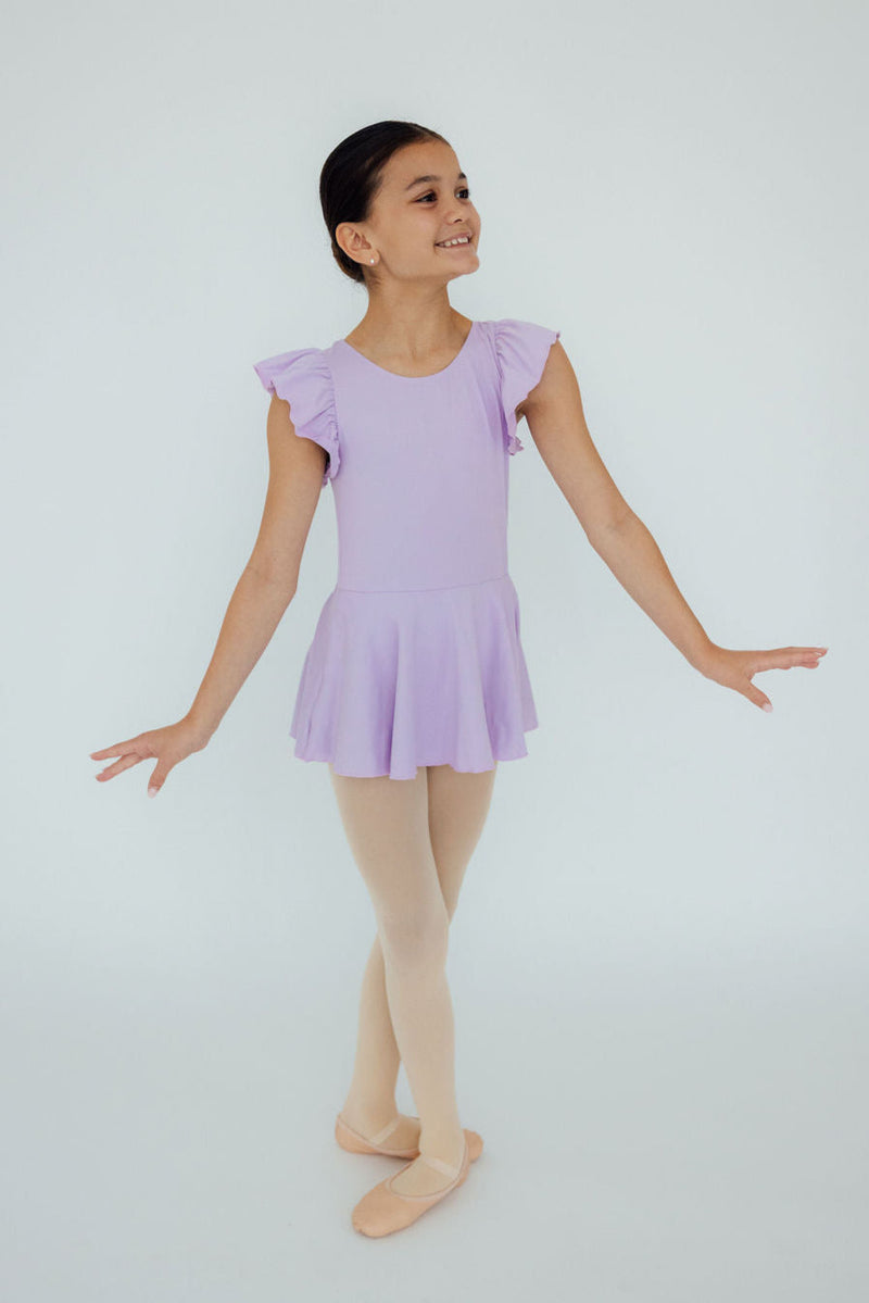 A young ballerina wearing the Lavender S/S Twirl Leotard by Mila & Rose, gracefully posed and ready to shine in her dance class.