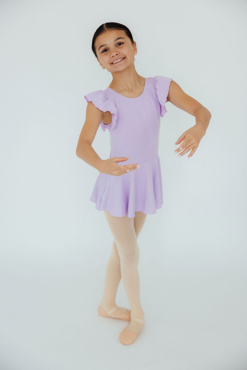 Charming young girl poses gracefully in the Lavender S/S Twirl Leotard by Mila & Rose, radiating confidence with a flowy skirt and soft lavender color.