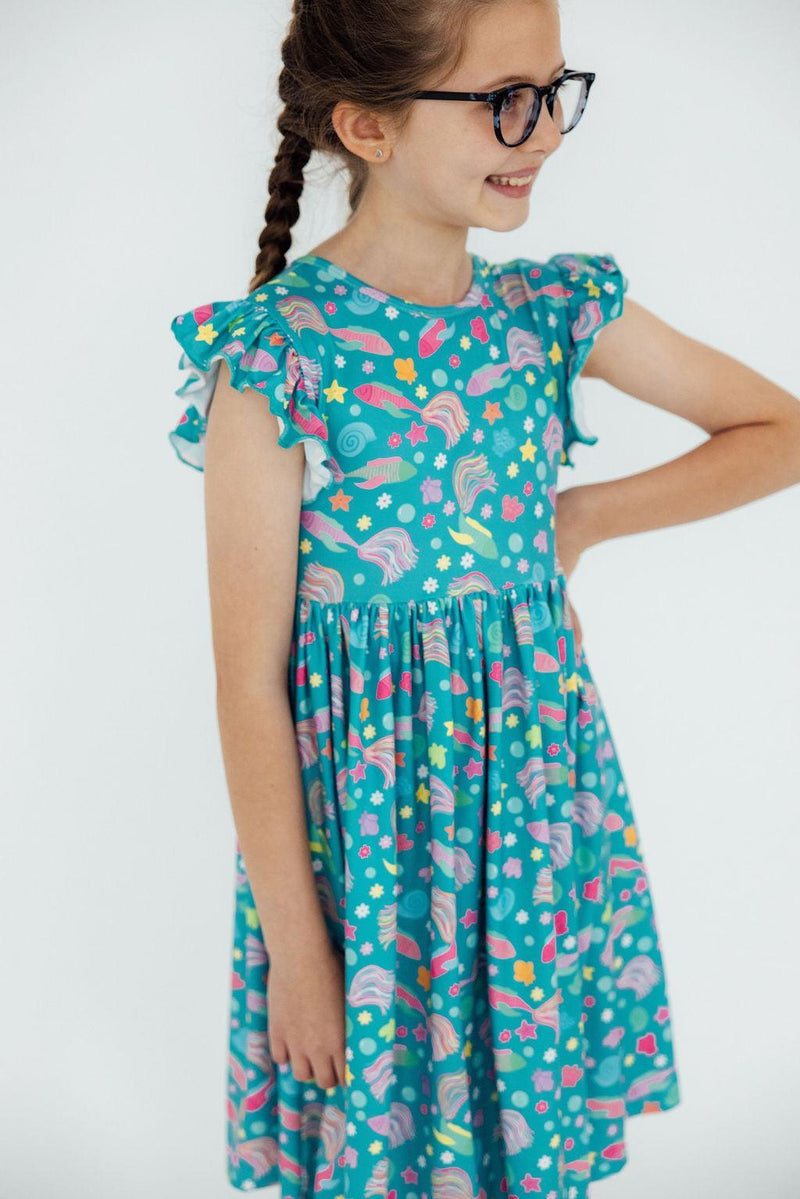 Girl wearing the Betta Blooms Flutter Sleeve Twirl Dress, joyfully twirling during playtime.