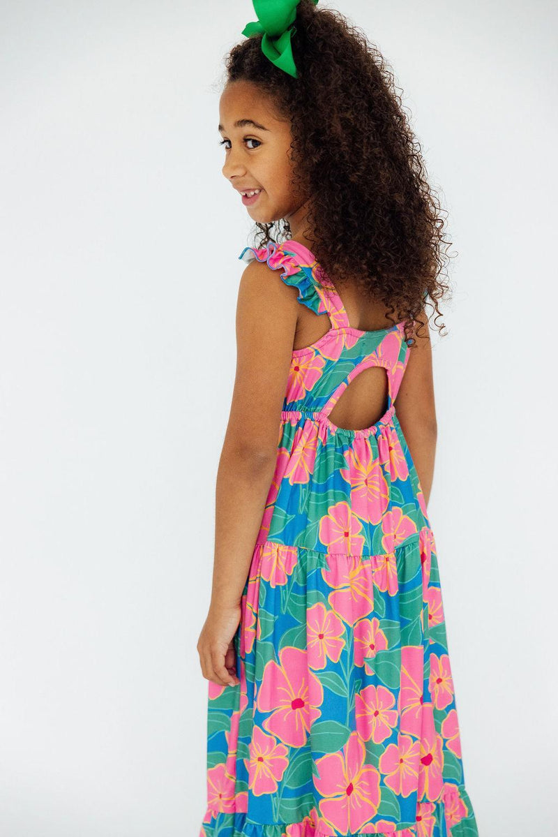 The back view of a girl in the Luau Floral Ruffle Maxi Dress showcasing its cute cutout design and charming ruffle details for a playful summer look.