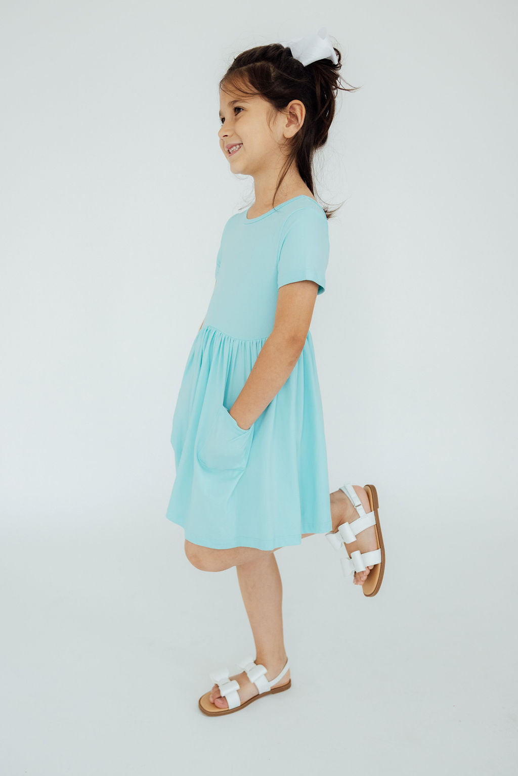 Aqua S/S Pocket Twirl Dress showcased on a smiling girl, highlighting the dress's stylish silhouette and convenient pockets, perfect for active little ones.