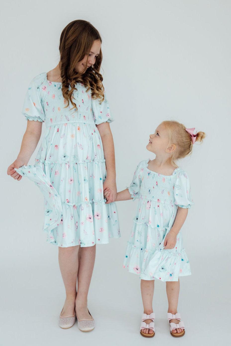 Little girl wearing the Butterfly Ballet Smocked Ruffle Dress by Mila & Rose, twirling joyfully in a sunny garden.