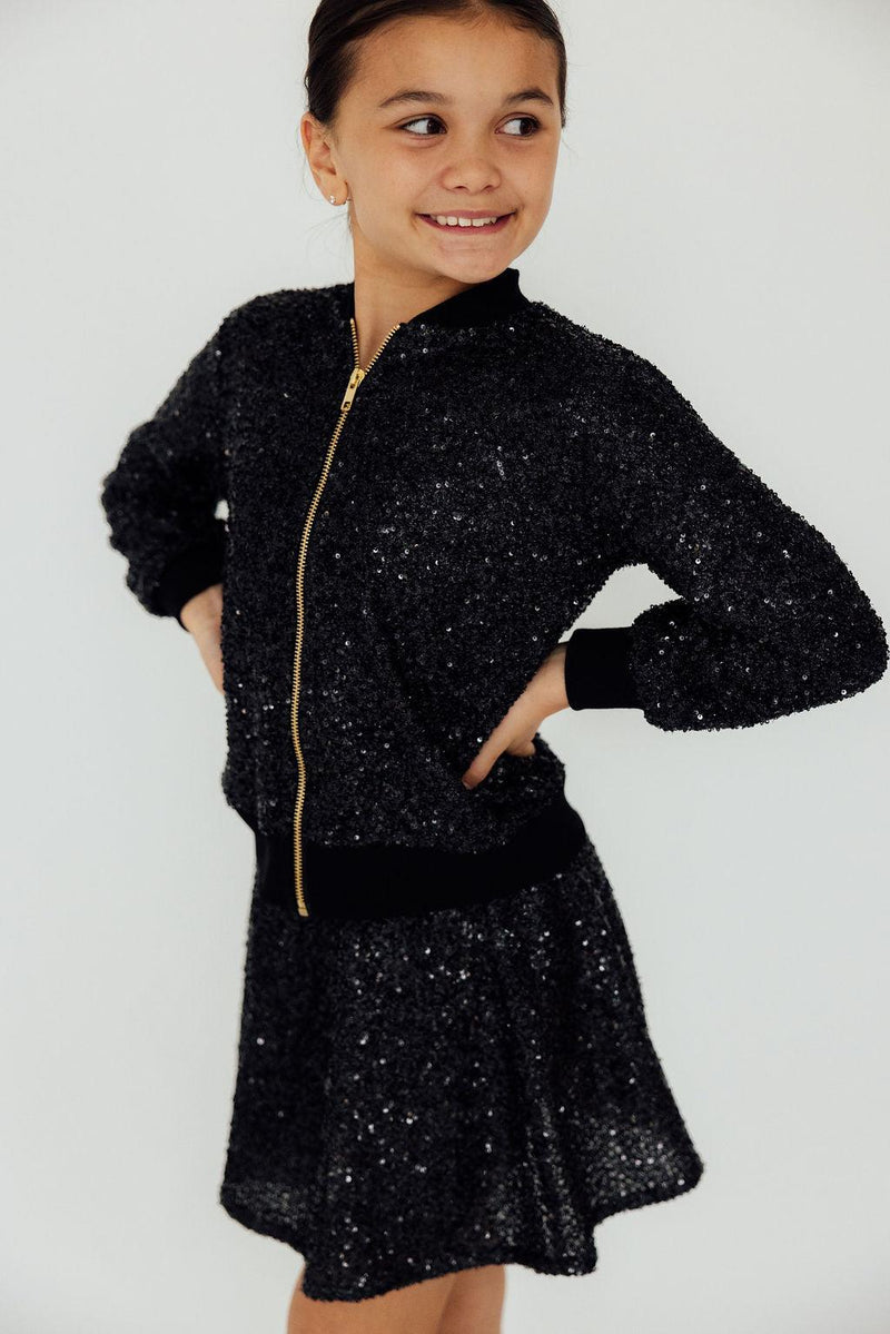 A model wearing the Black Sequin Twirl Skort from Mila & Rose, styled with trendy accessories for a chic party look.