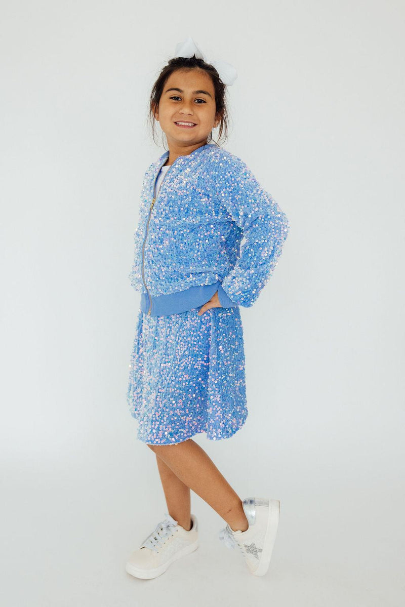 Happy girl demonstrating her playful side in a Light Blue Velvet Sequin Jacket and skirt, ready to shine from every angle.