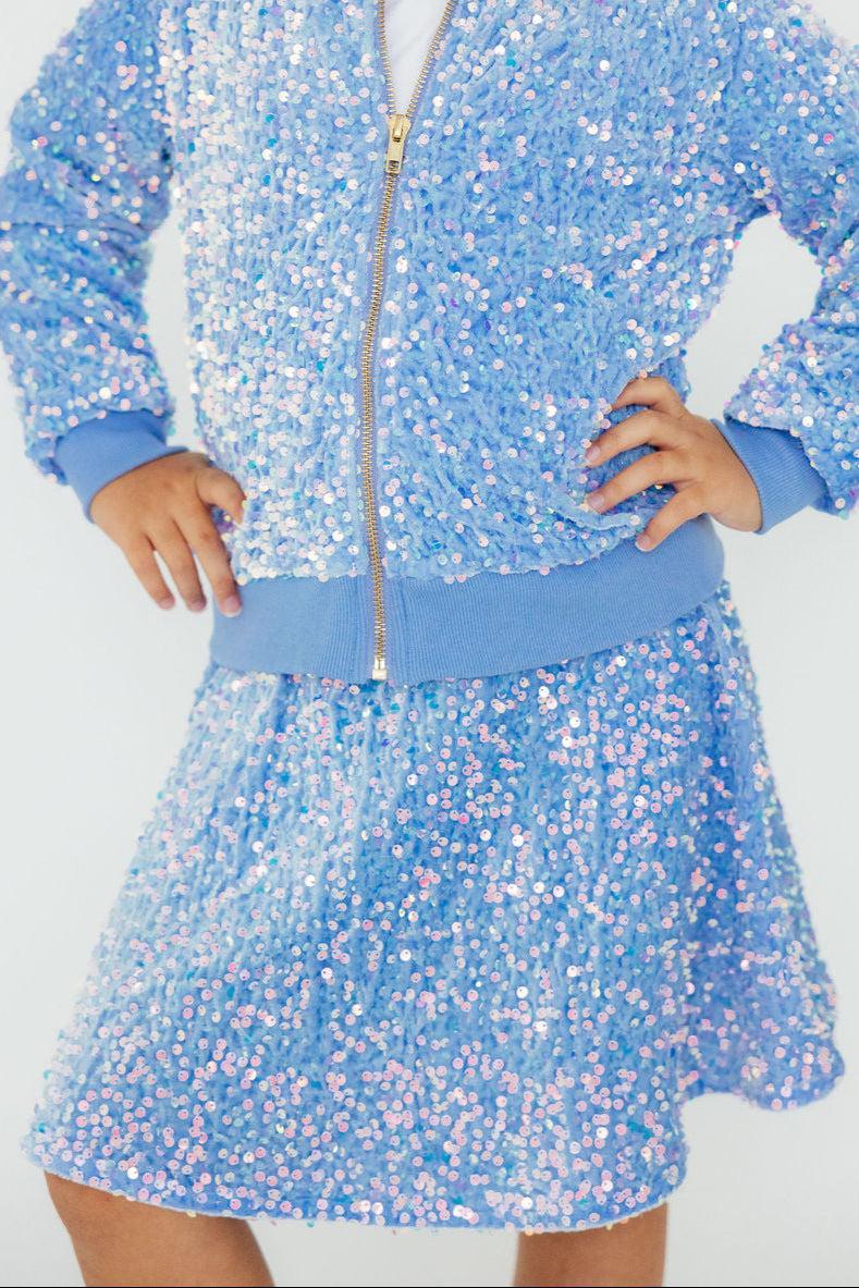 Young girl striking a pose in a Light Blue Velvet Sequin Jacket paired with a matching skirt, showcasing its shimmering sequins and vibrant color.