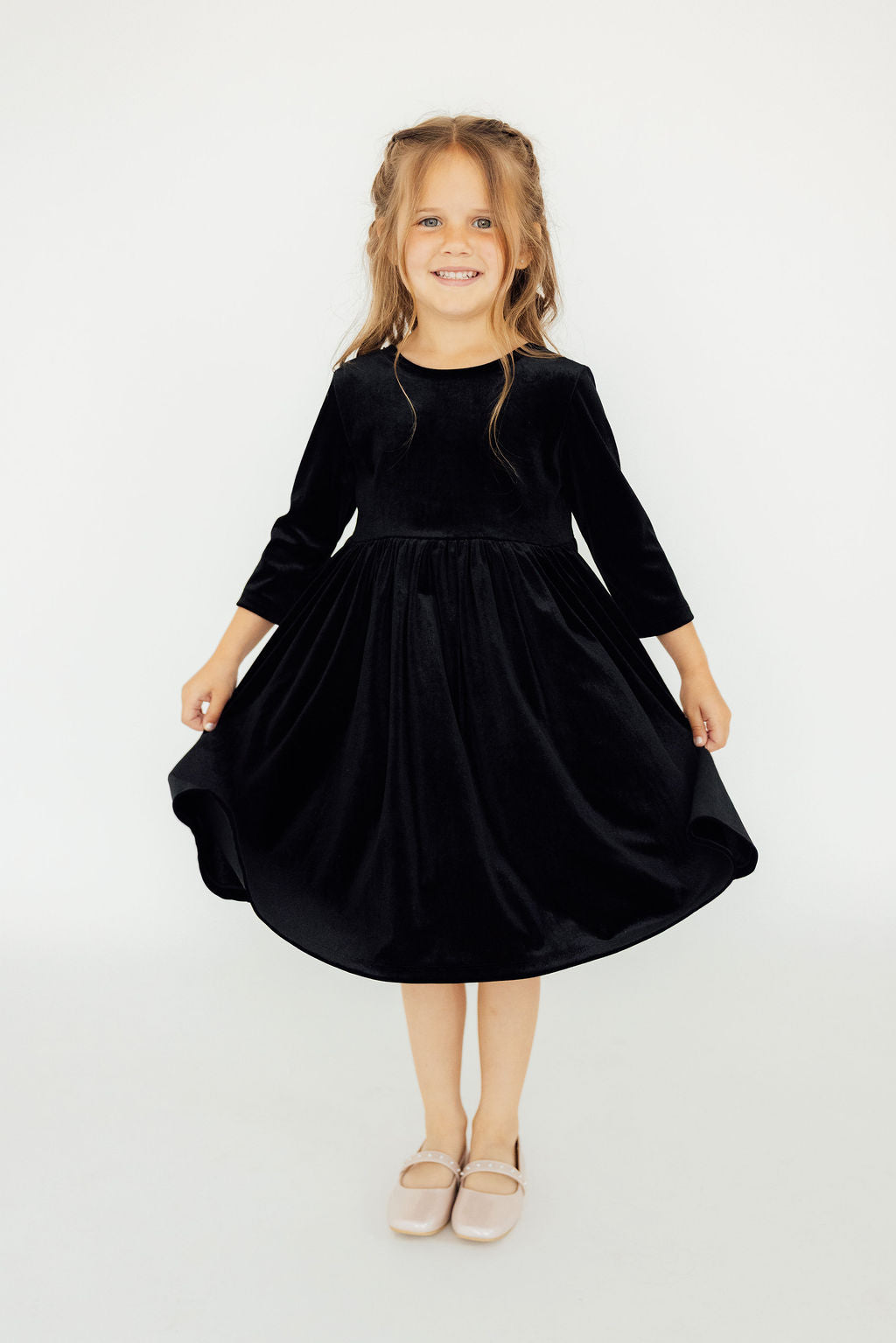 Smiling girl wearing the SALE Black Velvet Twirl Dress from Mila & Rose®, showcasing its elegant design and playful twirl.