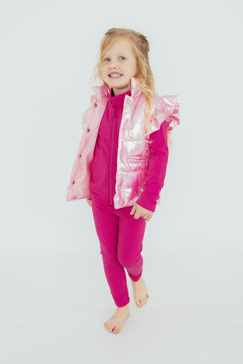 A happy little girl in the Pink Iridescent Puffer Vest from Mila & Rose ®, radiating charm and warmth while showing off her stylish outfit.