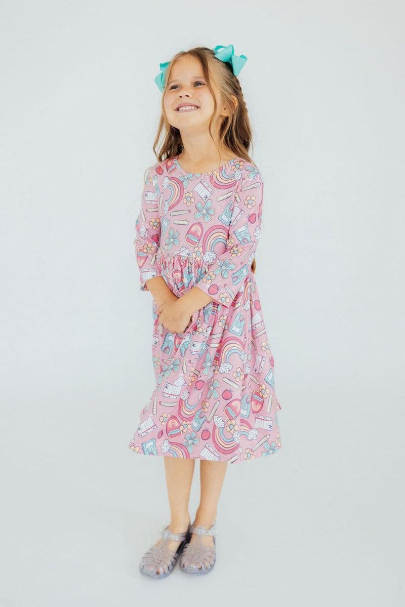 A joyful little girl in the Dream Big Little One 3/4 Pocket Twirl Dress, showcasing the playful design while standing with a cheerful expression.