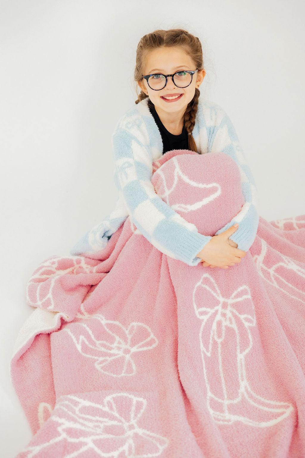 A cheerful girl in glasses holds the Light Pink Cowgirl Cozy Blanket, radiating warmth and comfort in a stylish pose.