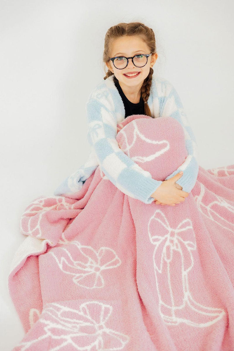 A cheerful girl in glasses holds the Light Pink Cowgirl Cozy Blanket, radiating warmth and comfort in a stylish pose.