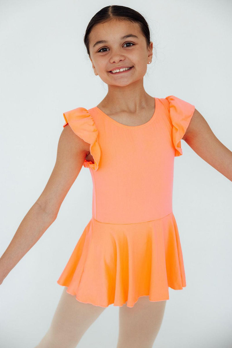 Smiling child in the Neon Coral Short Sleeve Twirl Leotard, showcasing a vibrant coral color and playful ruffled sleeves.