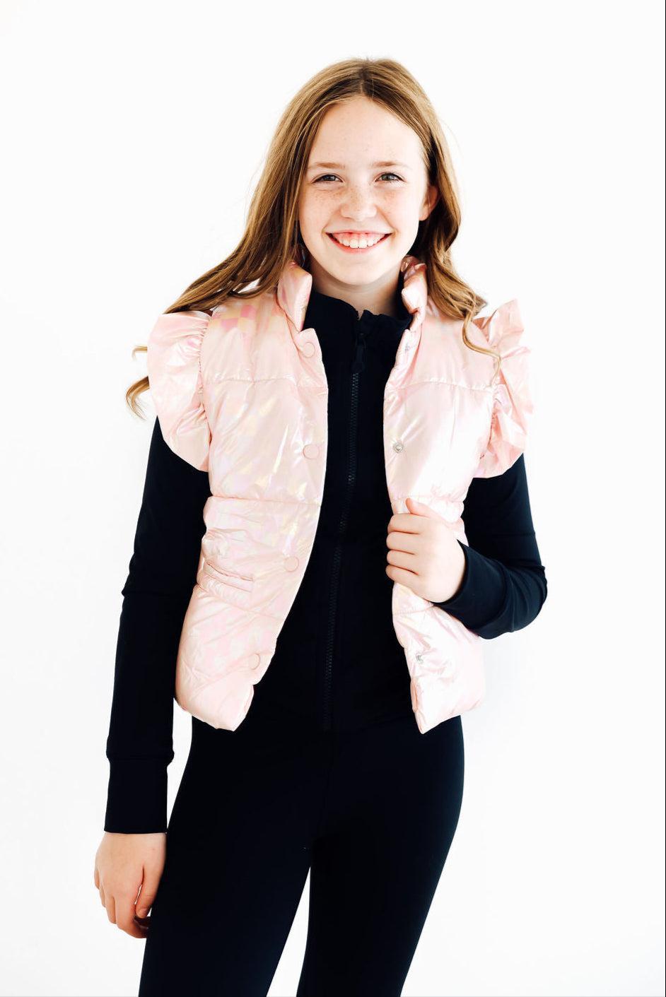Charming child wearing a Light Pink Checker Puffer Vest, showcasing playful ruffles and style against a bright background.