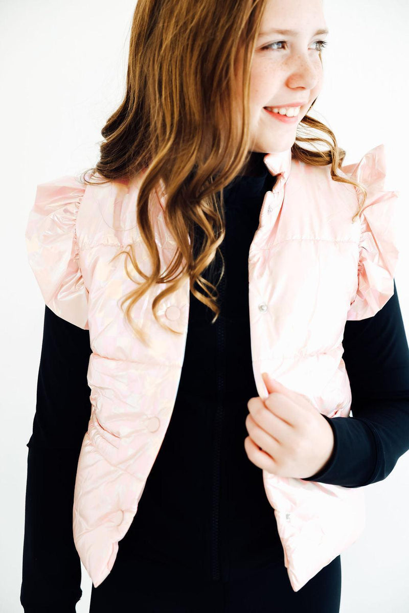 Beaming girl in a Light Pink Checker Puffer Vest, elegantly styled against a light backdrop, exuding charm and warmth.