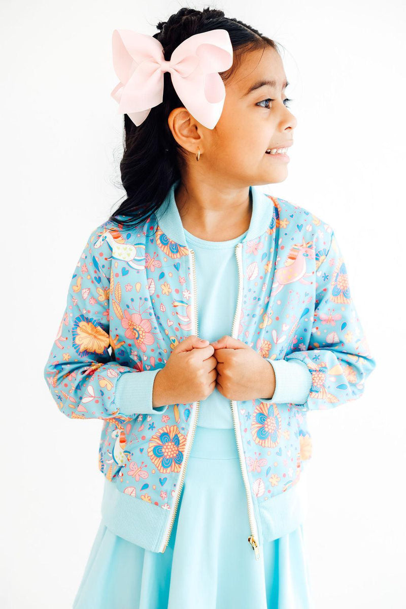 Close-up view of the Blue Retro Unicorns Satin Jacket fabric, highlighting the vibrant unicorn graphics against a blue background.