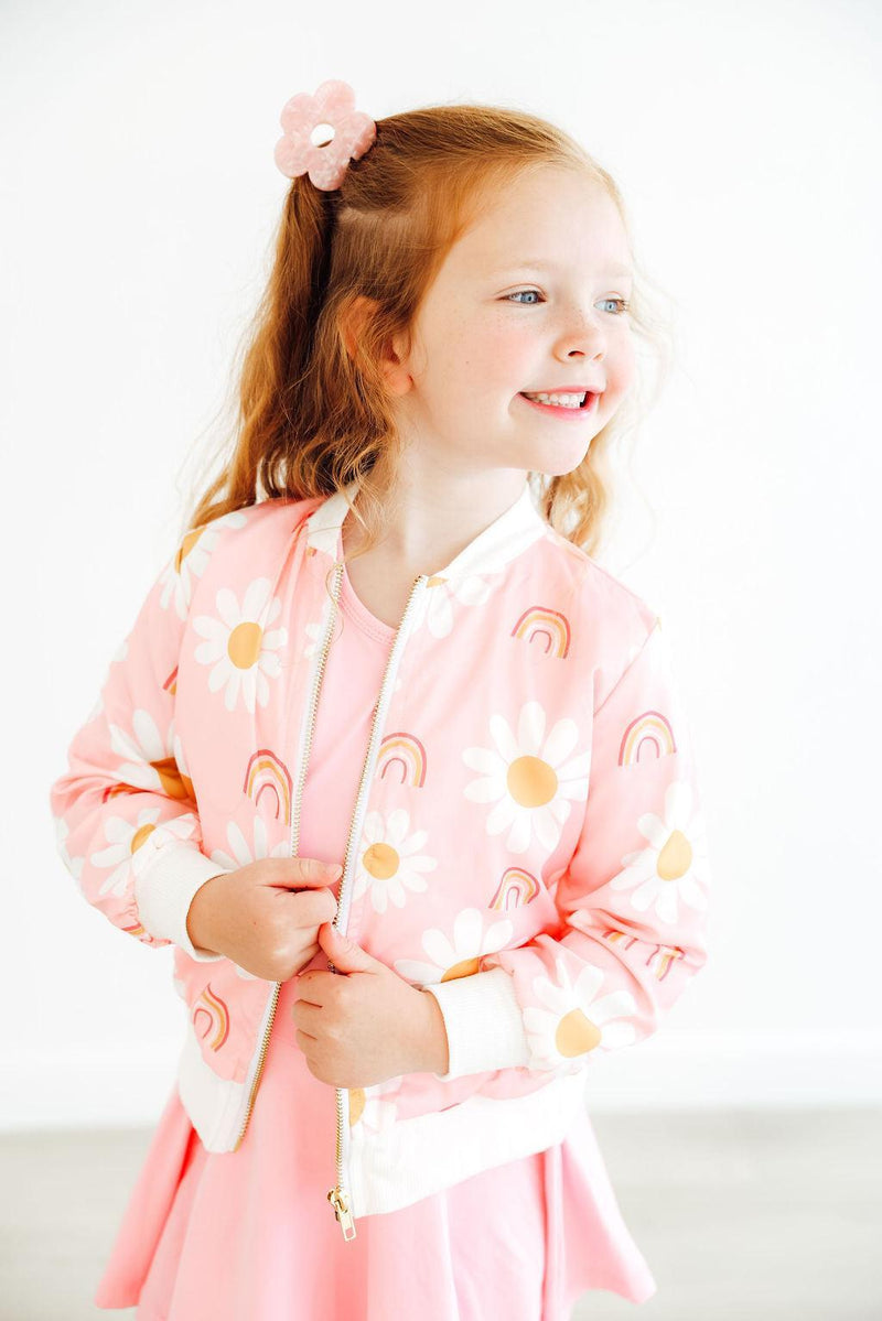 Side view of a girl wearing the You are My Sunshine Satin Jacket from Mila & Rose®, with a charming smile and styled hair, emphasizing the playful design of the jacket against a simple background.