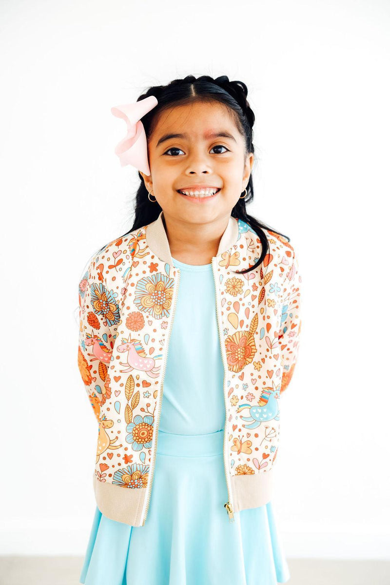 Girl enjoying a confident pose in the 'Retro Unicorns' satin jacket for girls, accentuating the unique design against a simple background.
