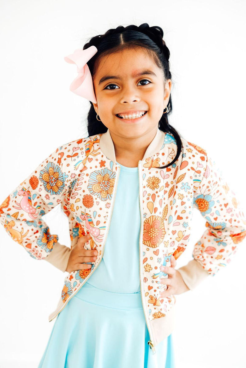 Happy girl posing in the 'Retro Unicorns' satin jacket for girls, smiling with hands on her hips, ideal for playful fashion.