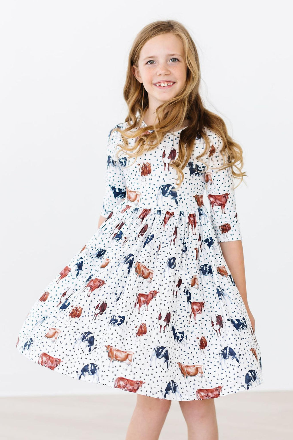 Girl in a Moo Meadows 3/4 Sleeve Pocket Twirl Dress by Mila & Rose, showcasing a playful design with farm animals on a polka dot background, perfect for twirling and play. Ideal for school or casual events.