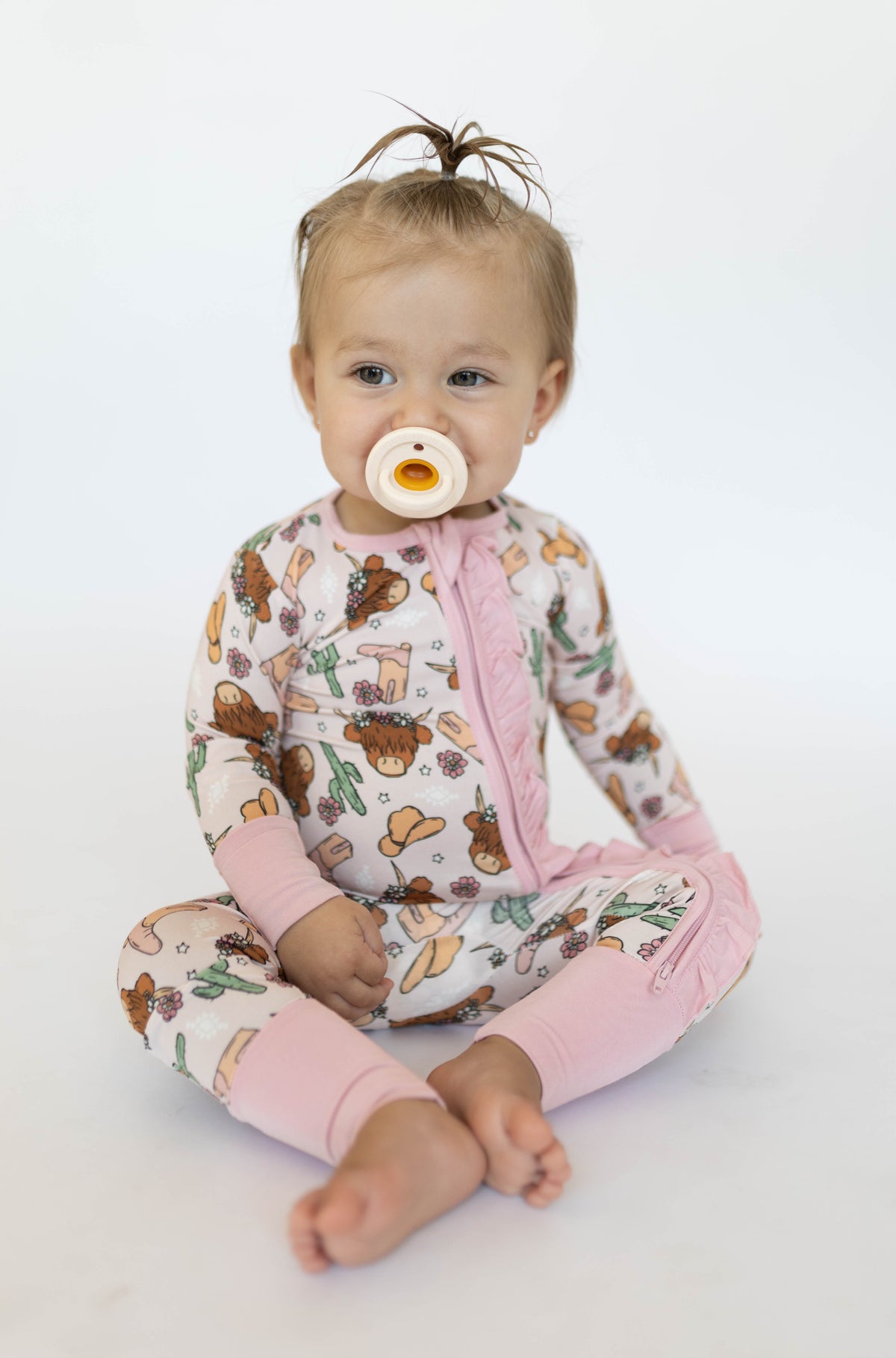 Toddler wearing pink western-themed convertible onesie with solid cuffs