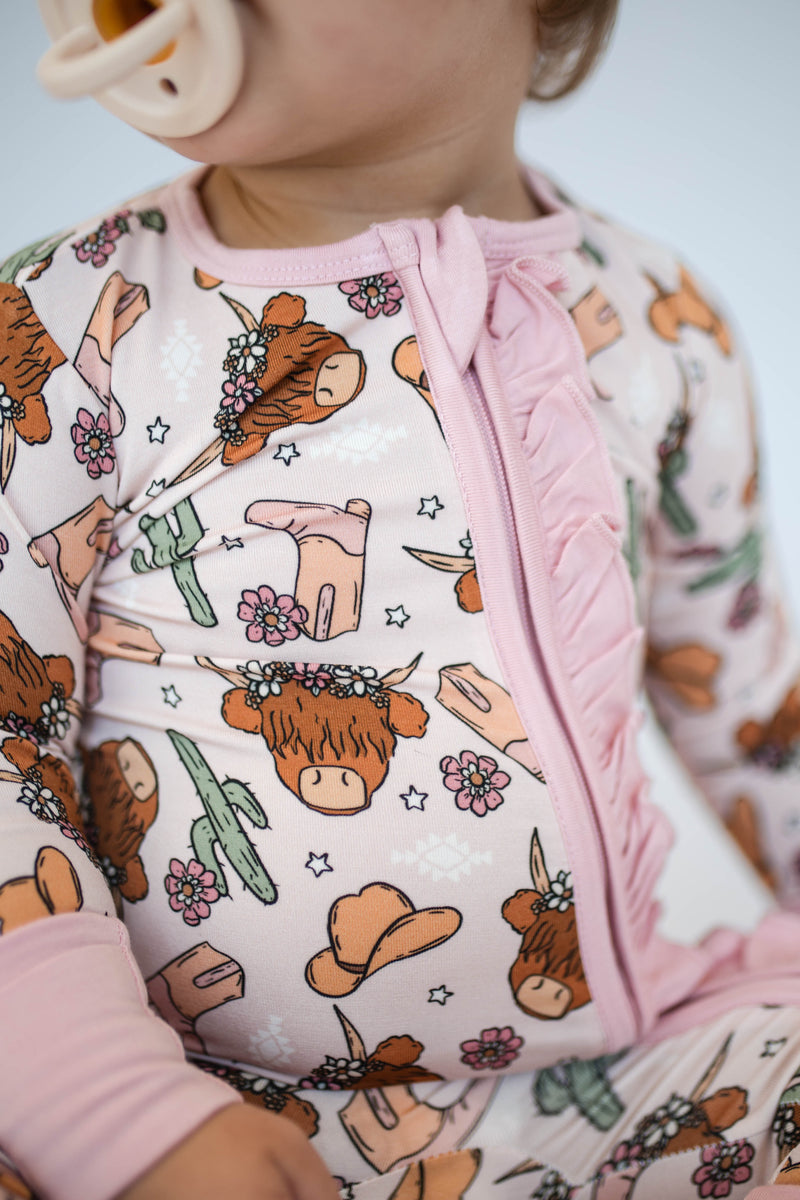 Close-up of pink bamboo fabric with Highland cow print and ruffled zipper guard