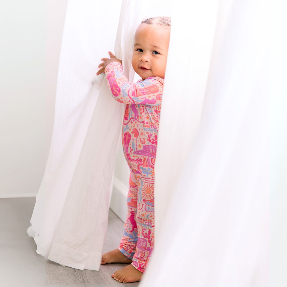 Happy baby in the Second-Skin Footless Romper | Saddle Up Western Themed, embodying comfort and cuteness in this stylish bamboo baby romper.