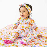 Baby wearing pink The SoftKnot Bow head-wrap with Here Comes the Sunshine print, smiling.