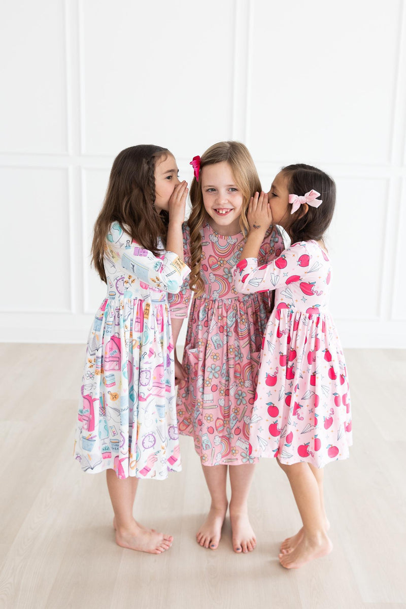 Three young girls enjoying playtime in the Star Student 3/4 Sleeve Pocket Twirl Dress by Mila & Rose®, showcasing vibrant patterns and fun twirls.