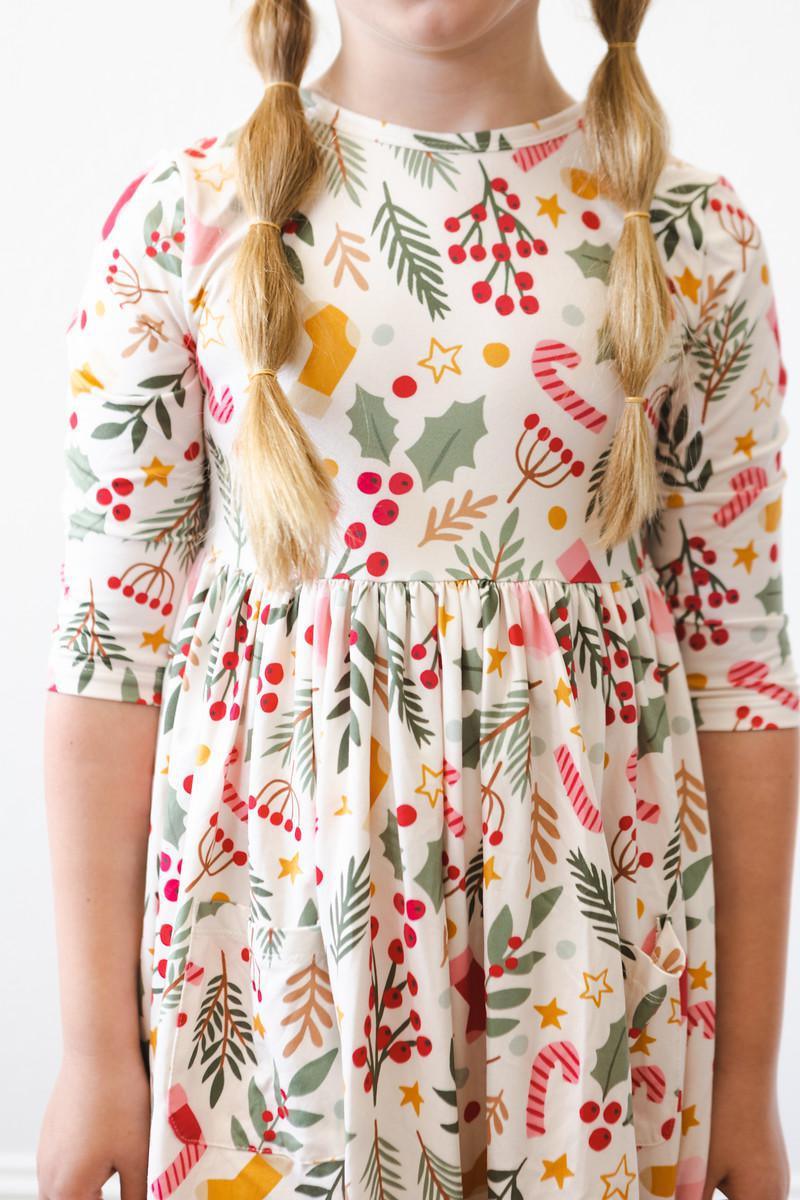 A close-up shot of a girl wearing the 'Holly Jolly Christmas' 3/4 Sleeve Pocket Christmas Twirl Dress for Girls, capturing the colorful details of the dress.