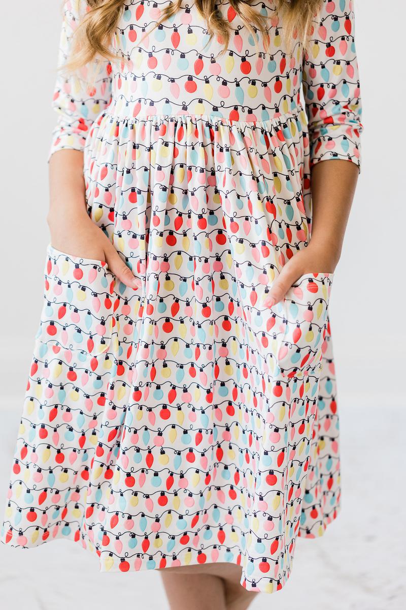 Merry & Bright 3/4 Sleeve Pocket Twirl Dress featuring a colorful festive design with playful lights, designed by Mila & Rose®, perfect for twirling and playtime.