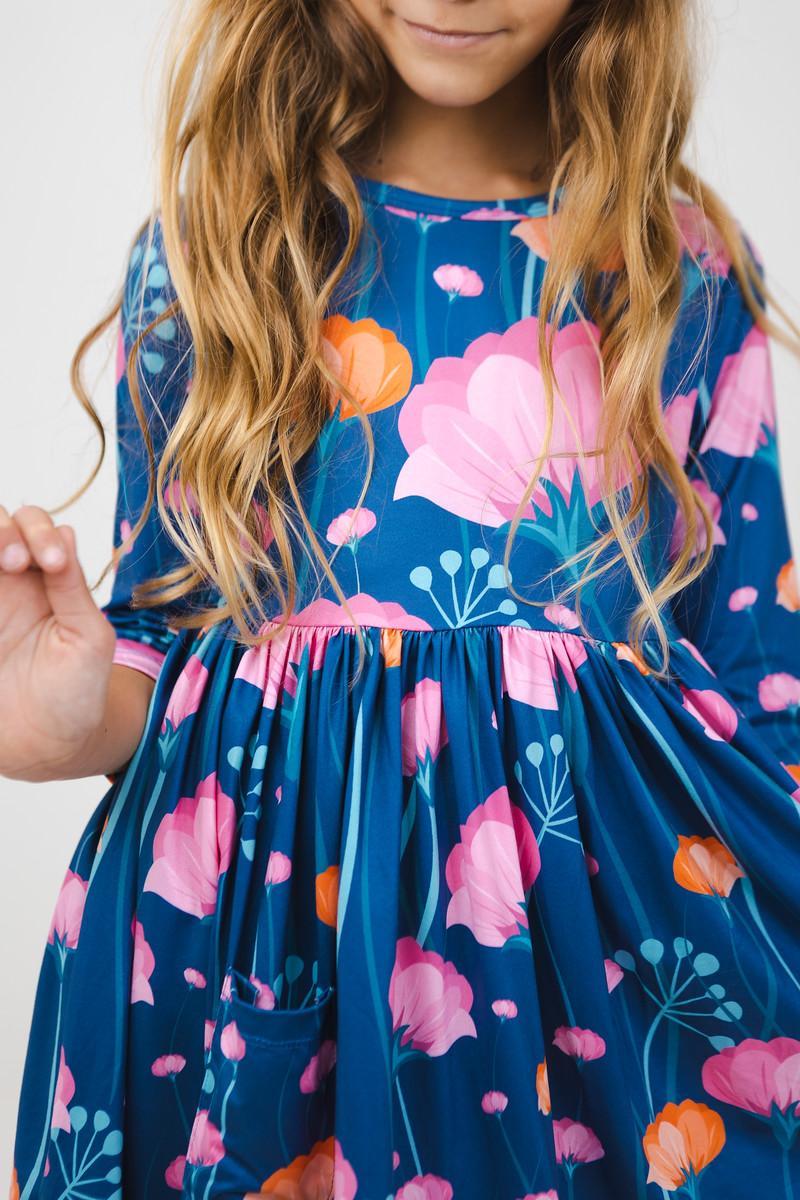 A delightful close-up of the Poppies 3/4 Sleeve Pocket Twirl Dress featuring vibrant floral patterns in pink and blue. Perfect for twirling adventures, this dress combines style with practicality for little ones.