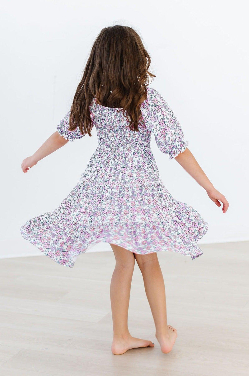 A girl spins around in the Lovely Lavender Smocked Ruffle Dress, allowing the fun ruffle skirt to catch the light, perfect for dancing and play.
