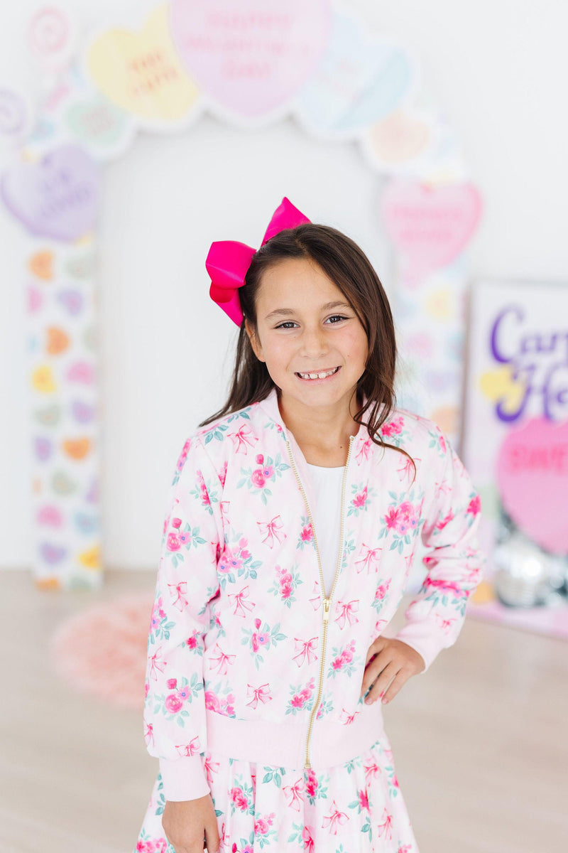 Charming girl wearing the Gingham Bows Satin Jacket by Mila & Rose, showcasing her playful style with a bright pink bow in her hair, ready to twirl into fashion fun!