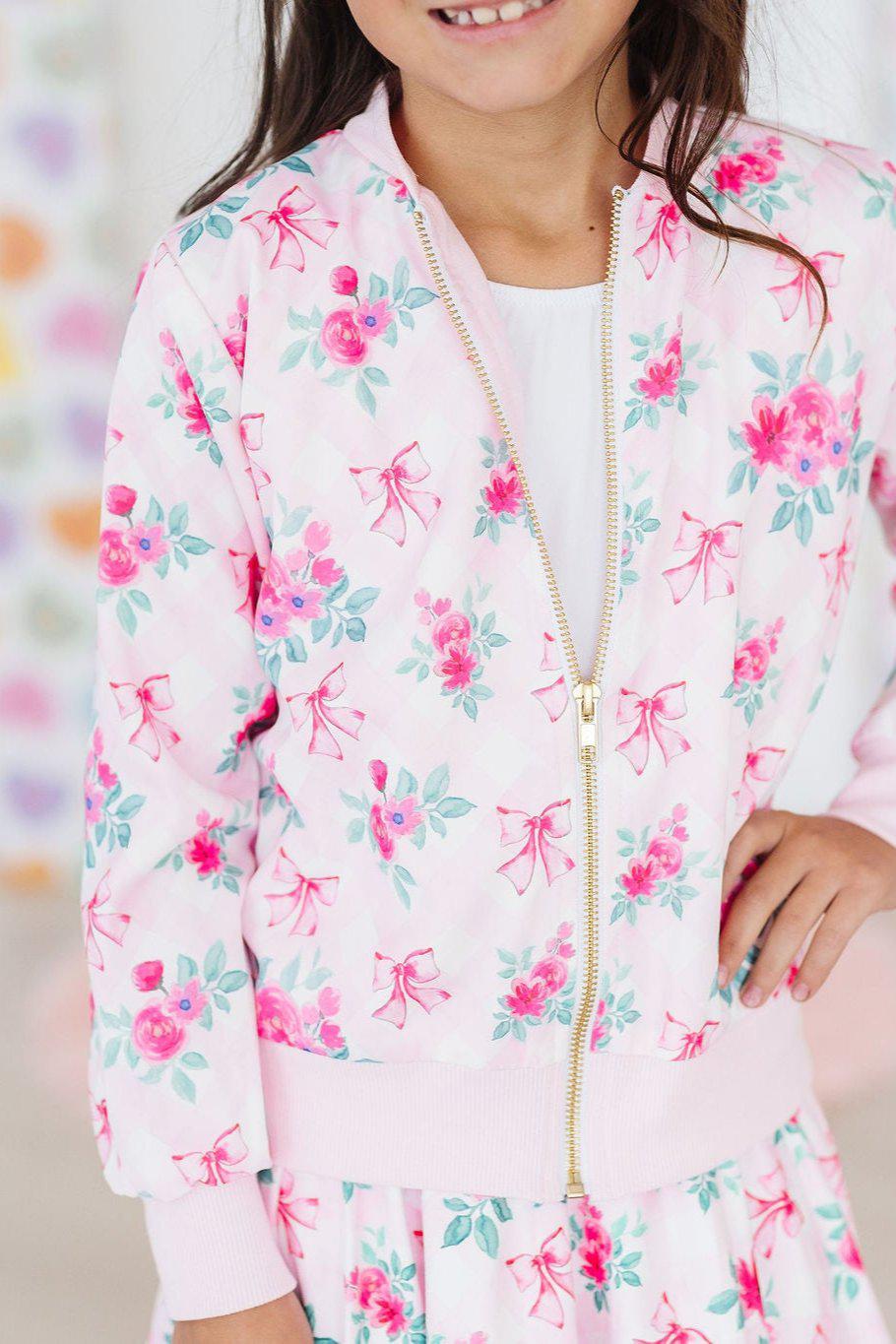 Charming Gingham Bows Satin Jacket showcased on a young girl, featuring a floral print with pink bows, perfect for adding flair to any outfit.