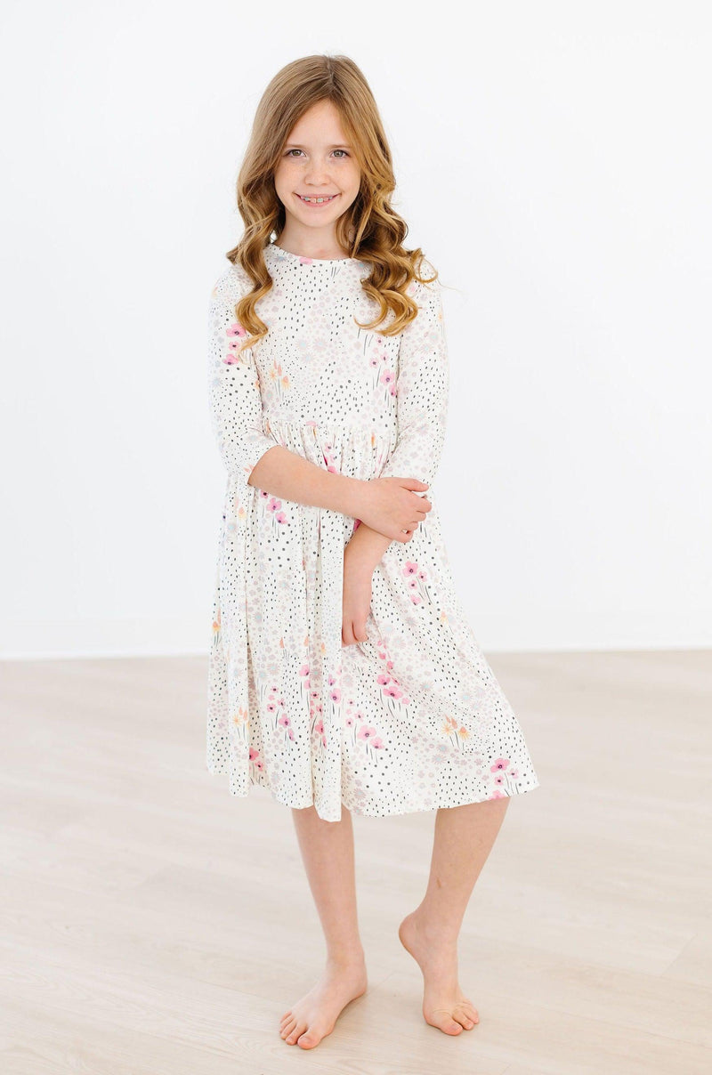 Whimsical Wildflowers 3/4 Sleeve Pocket Twirl Dress worn by a young girl, showcasing its charming design and vibrant floral patterns, perfect for any occasion.