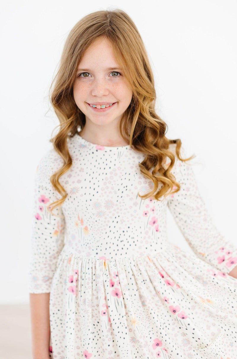 Close-up of a young girl wearing the Whimsical Wildflowers 3/4 Sleeve Pocket Twirl Dress, highlighting the beautiful floral pattern and comfortable fit.