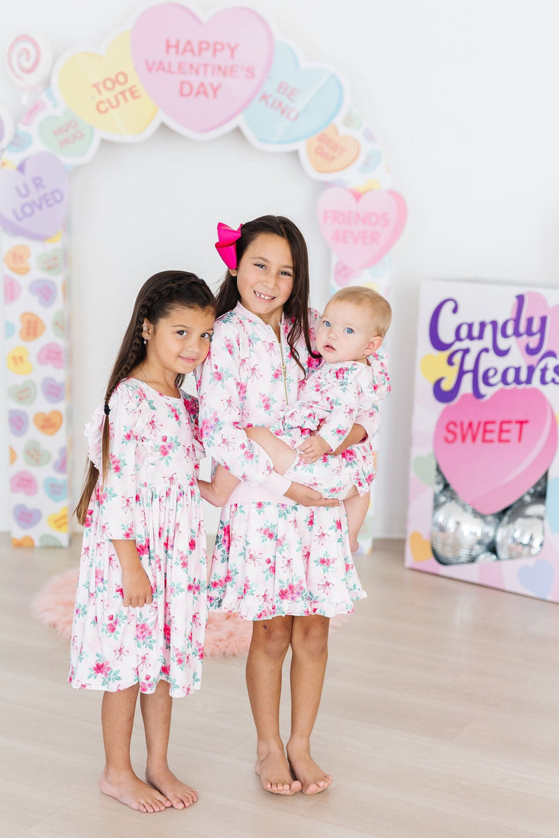 Three delighted kids wearing matching floral dresses, including the Gingham Bows Ruffle Twirl Skort by Mila & Rose, posing in a fun, colorful setting perfect for memorable playdates.