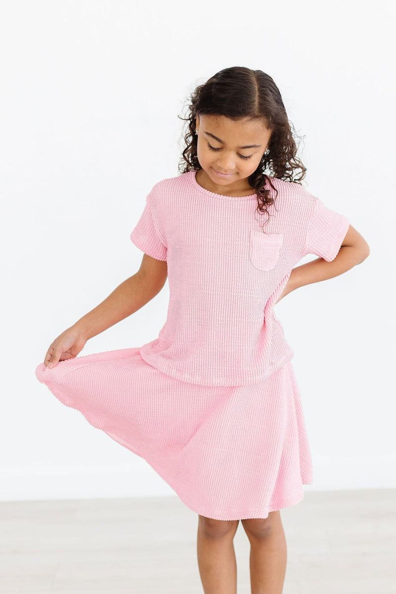 Stylish model wearing the Bubblegum Pink Scrunchy Pocket Tee paired with trendy skorts, showcasing a coordinated and fashionable look.