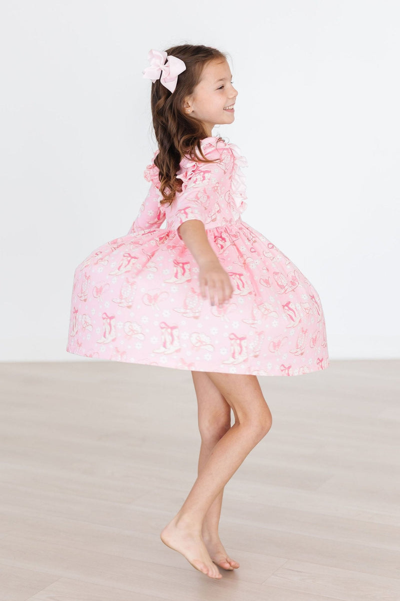 Playful twirl moment captured in a Howdy 3/4 Sleeve Ruffle Twirl Dress by Mila & Rose®, featuring a joyful girl spinning in her flared pink dress.