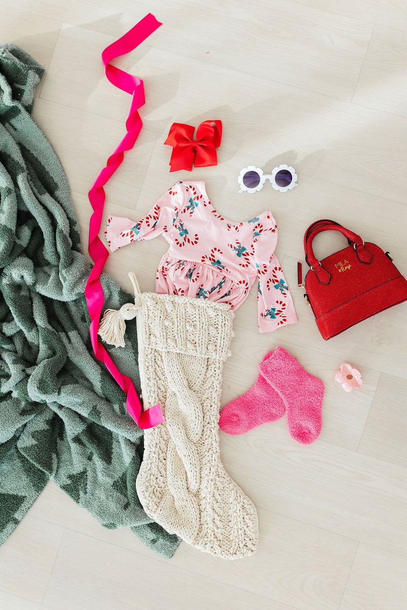 Candy Cane Cutie 3/4 Sleeve Pocket Twirl Dress by Mila & Rose displayed with festive holiday accessories, including colorful socks, a decorative stocking, and toys, ideal for Christmas celebrations.