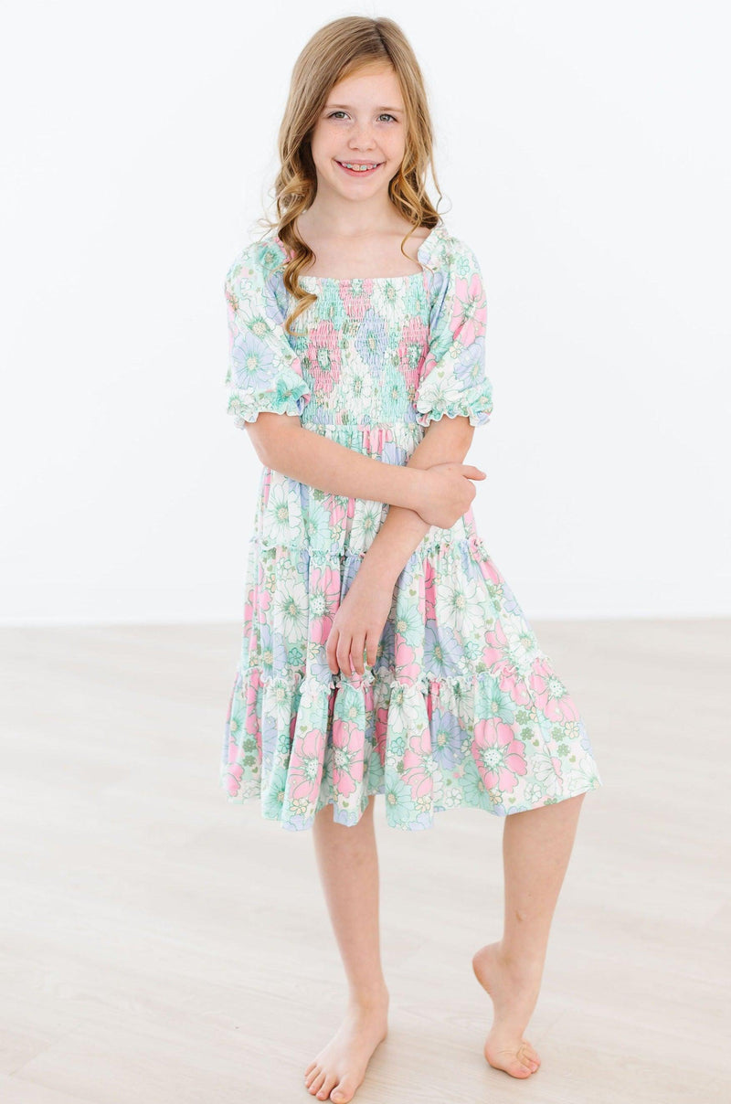 Radiant girl posing in the Minty Meadow Smocked Ruffle Dress, showing off the charming ruffled skirt and elegant smocked detail.