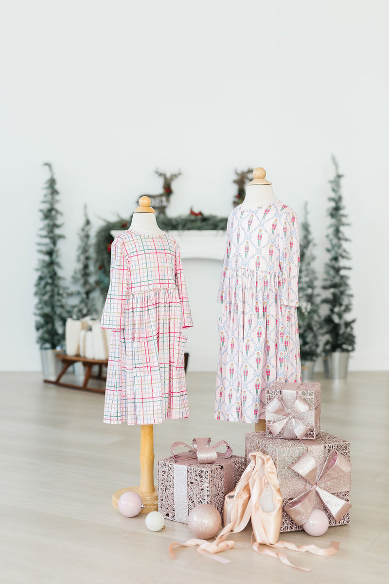 Charming display of the Pink Plaid 3/4 Sleeve Pocket Twirl Dress alongside a festive setting, ready for holiday magic.