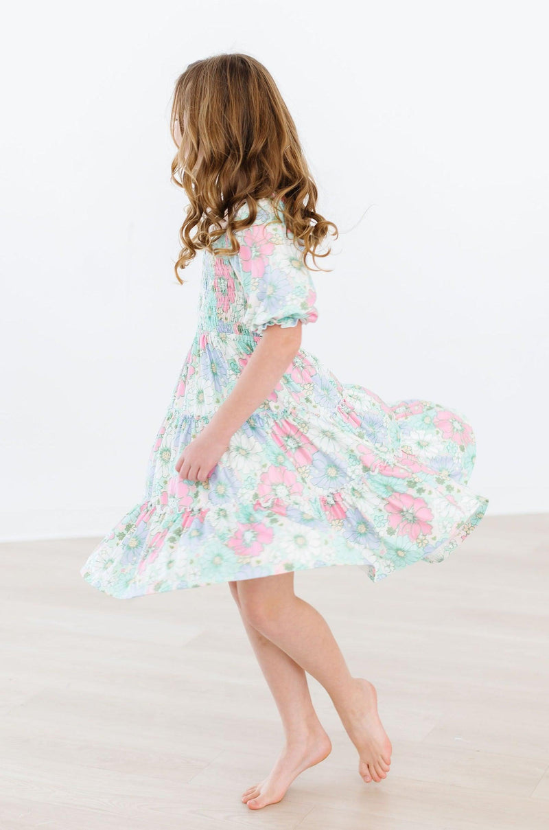 Joyful girl twirling in the Minty Meadow Smocked Ruffle Dress, capturing the dress's lively flow and vibrant pastel colors.
