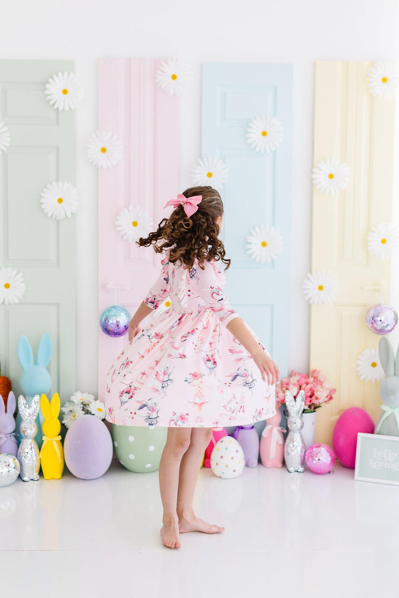 A happy child wearing the Ballet Beauties Ruffle Twirl Dress by Mila & Rose, styled with ballet flats, radiating joy and elegance during a special occasion.