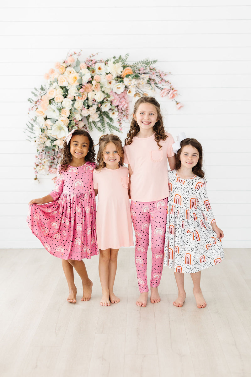 Group of charming girls displaying various styles, including the Peach Rainbow 3/4 Sleeve Pocket Twirl Dress, surrounded by beautiful floral decor, perfect for playful and stylish moments together.