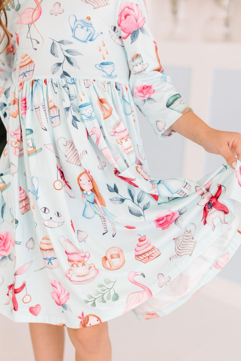 A close-up view of the skirt of the Wonderland 3/4 Sleeve Pocket Twirl Dress, featuring whimsical motifs like cupcakes, flamingos, and flowers, perfect for little fashion lovers.
